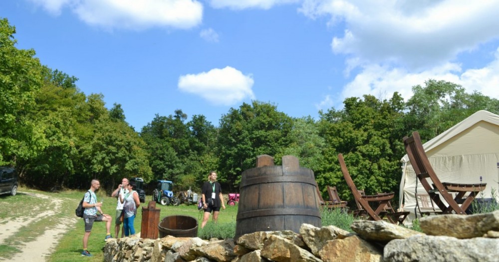 Drevený sud a v pozadí pár návštevníkov vinárskeho festivalu
